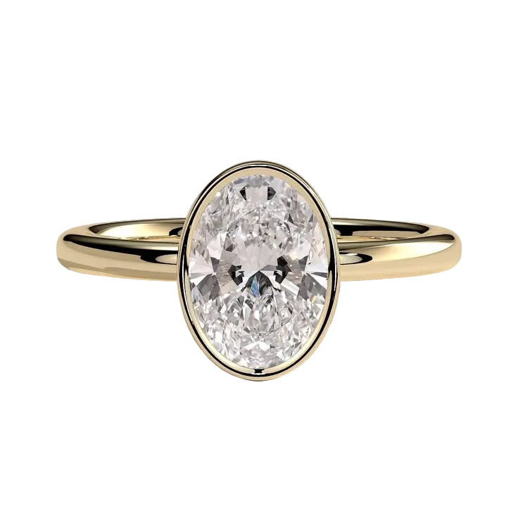 An oval-cut diamond engagement ring set in a polished yellow gold band, photographed on a clean, light gray reflective surface.