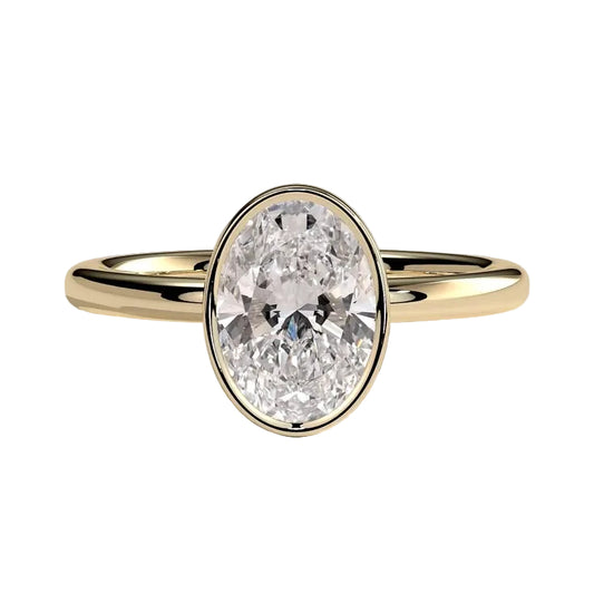 An oval-cut diamond engagement ring set in a polished yellow gold band, photographed on a clean, light gray reflective surface.